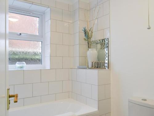 La salle de bains est pourvue de carrelage blanc, d'une baignoire et d'une fenêtre. dans l'établissement The Sashes - Apartment One - FREE Parking - Ultrafast WIFI - Smart TV - Netflix - sleeps up to 6! Close to Poole Town Center & Sandbanks & Bournemouth, à Poole