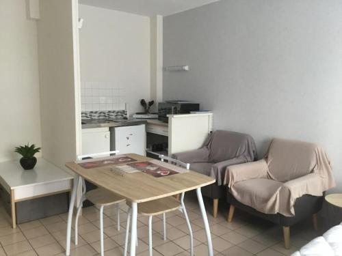 une cuisine avec une table et des chaises dans une pièce dans l'établissement Studio meublé 27 mètres carrés wifi netflix, à Niort