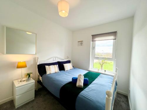 a bedroom with a blue bed and a window at Luxurious & Modern Apartment in Hawkhead