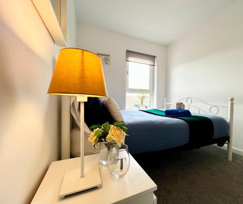 a bedroom with a bed and a lamp on a table at Luxurious & Modern Apartment in Hawkhead