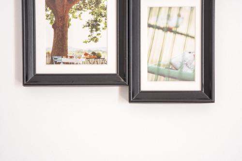 two framed pictures of a table and a tree on a wall at Cozy Budget Apartments in the Heart of Fira in Fira