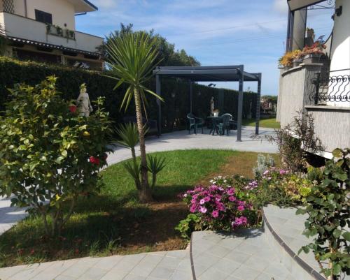 a garden with a patio with a palm tree and flowers at Appartamento in Residenza Punta di Sabaudia - seminterrato in Sabaudia
