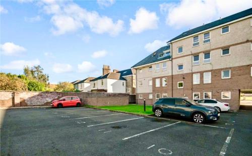 two cars parked in a parking lot in front of a building at Luxurious & Modern Apartment in Hawkhead