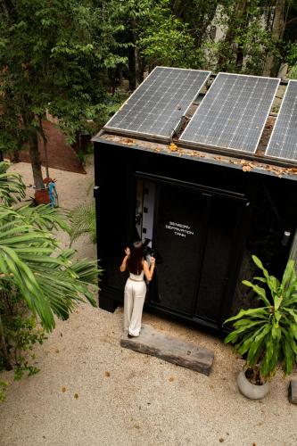 a woman taking a picture of a building with solar panels at Bufo Alvarius in Tulum