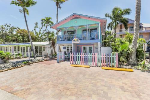 a house with a pink fence and palm trees at Lantana Suite in Captiva