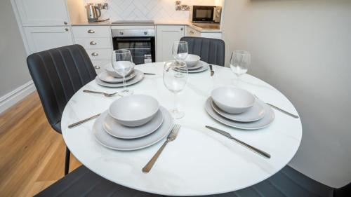 a white dining room table with plates and wine glasses at Modern 2 BDR apartment at Queens by Belfast City Breaks in Belfast