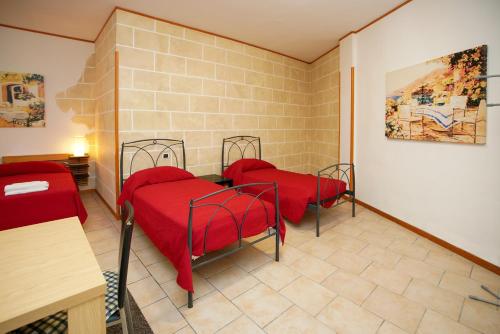 2 letti con coperte rosse in una camera di RESIDENCE LUPIAE a Lecce