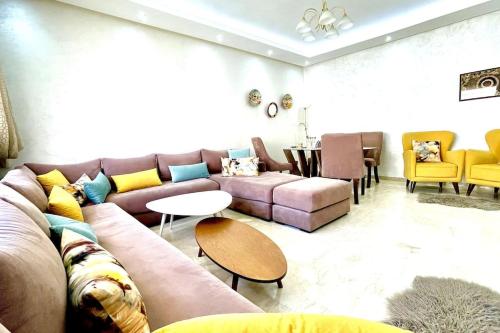 a living room with a couch and tables and yellow chairs at Taj nouaceur aéroport Mohamed V in Nouaseur