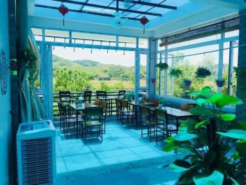 a restaurant with tables and chairs and a large window at Nana Lee Homestay Phong Nha in Cừ Lạc