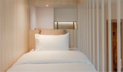 a bedroom with a bed with white sheets and a window at Punn Hotel Korat in Nakhon Ratchasima