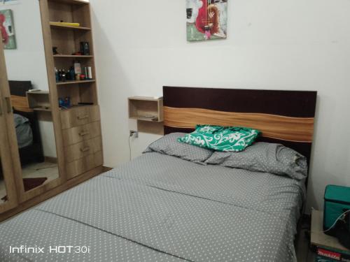 a small bedroom with a bed with a wooden headboard at Alojamiento y transporte in Guayaquil