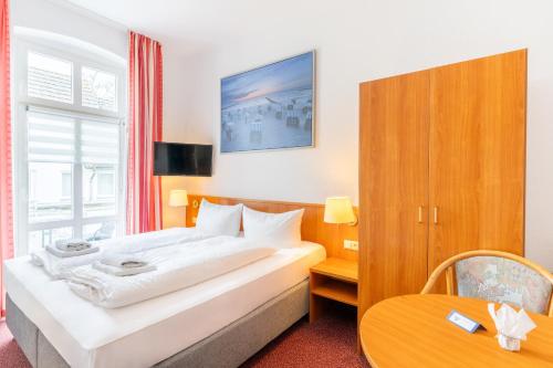 a hotel room with a bed and a table at Pension Wald und See in Ahlbeck