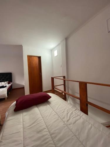 1 dormitorio con cama blanca grande y almohada roja en Work And Home en Cañuelas