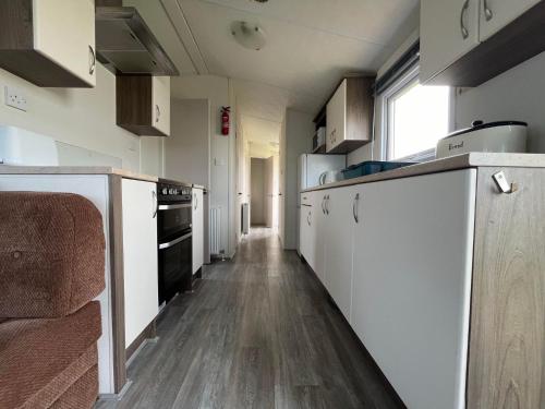 a kitchen with white appliances and a wooden floor at Ormesby 8, Haven Holiday Park, Caister - Four Bedroom, sleeps 8, pets welcome - 2 minutes from the beach! Entertainment passes required in Great Yarmouth