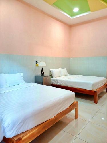 Duas camas num quarto com paredes cor-de-rosa em NGUYỆT MINH HOTEL em Ấp Phú Lợi