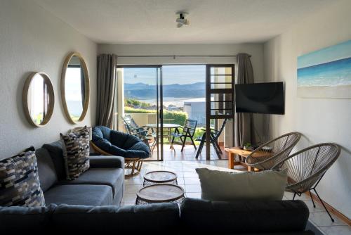 a living room with a couch and chairs and a balcony at Seaviews from Arrowood in Plettenberg Bay