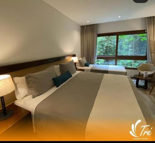 - un grand lit dans une chambre avec une grande fenêtre dans l'établissement Hotel Tré Iguazú, à Puerto Iguazú