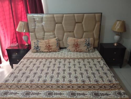 a bed with a large headboard and two night stands at Balqees Cottage in Lahore