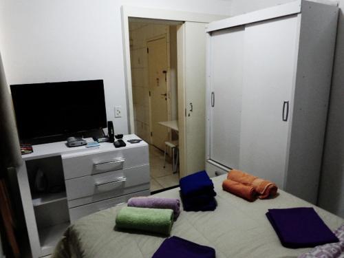 um quarto com uma cama com almofadas e uma televisão em Santana Temporada - Nossa Senhora de Copacabana Apartments no Rio de Janeiro