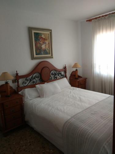 een slaapkamer met een bed en 2 nachtkastjes met een raam bij Un lujazo de piso en el centro de Calafell in Calafell