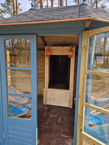 a greenhouse with a blue door and windows at Wioska pod Kogutem in Krępa