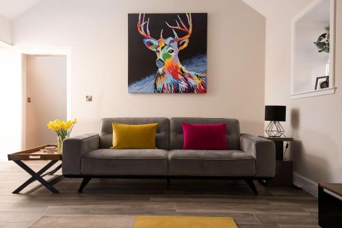 a living room with a couch and a painting of a deer at The Steading at West Lyham in Chatton