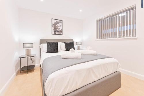 a white bedroom with a large bed with two lamps at Lovely 2 Bed Apartment in Burton-on-Trent in Burton upon Trent