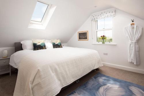 a white bedroom with a large bed and a window at The Star Barn in Ingram