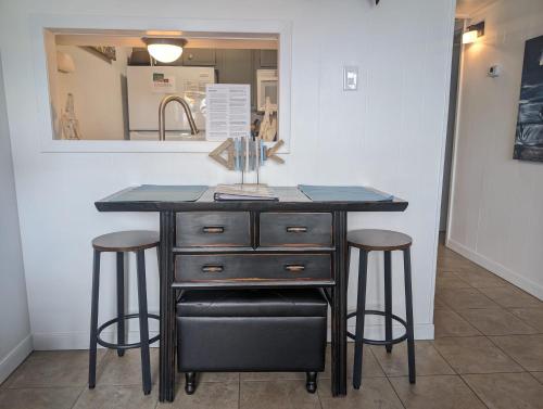 a kitchen island with two bar stools and a mirror at Blue Moon (Mustang Isle #11) in Port Aransas