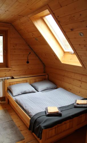 a bed in a wooden cabin with a window at Štýlový Zrub Martina B s pieckou a kúpacou kaďou! in Ždiar