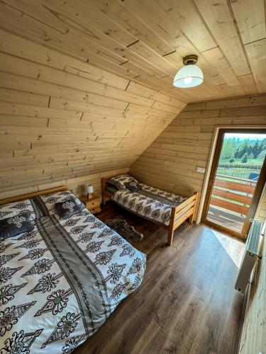 two beds in a room with a window at Domek Widokowy Tyniok in Koniaków