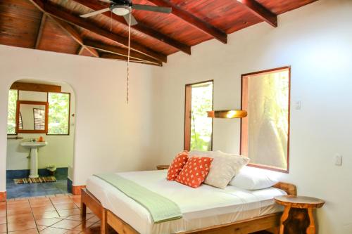 a bedroom with a bed with red pillows on it at Encanta La Vida in Cabo Matapalo