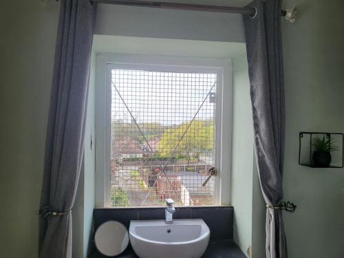 a bathroom with a sink and a large window at Jubilee pub in Litherland