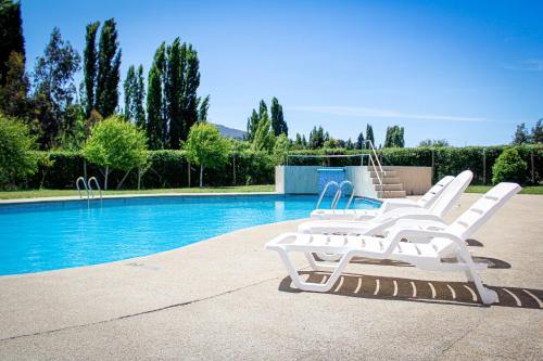 a group of white lounge chairs next to a swimming pool at Cabañas Buenavista Quillón in Quillón