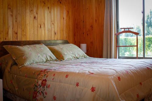 Cama en habitación de madera con ventana en Cabañas Buenavista Quillón en Quillón