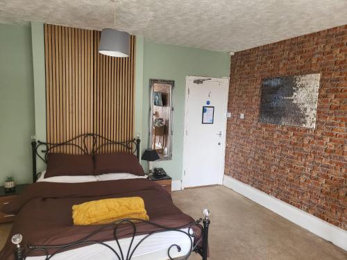 a bedroom with a bed and a brick wall at Jubilee pub in Litherland