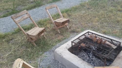 two chairs sitting next to a grill with a fire at Real African Life safaris and Camps in Lukungu