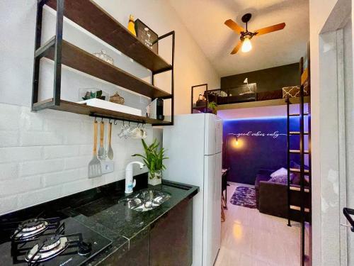 a kitchen with a black counter top and a refrigerator at Studios Tiny House - Viva Essa Experiência in Sao Paulo