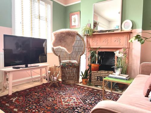a living room with a television and a cat standing on a chair at Vibrant Urban Retreat in Camberwell in London