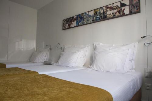 a hotel room with two beds with white pillows at Hotel Costa Verde in Póvoa de Varzim