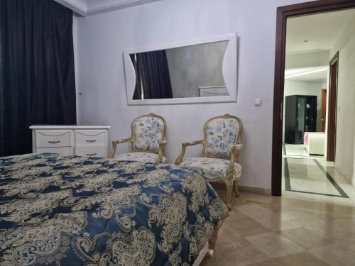 a bedroom with a bed and two chairs and a mirror at Diar Tunis Carthage II in Ariana