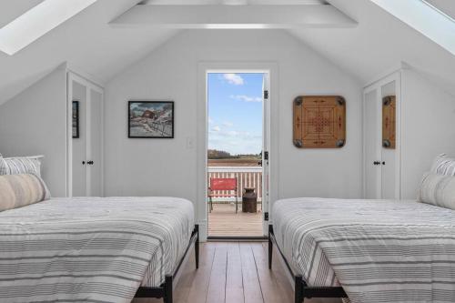 Cette chambre blanche dispose de 2 lits et d'un balcon. dans l'établissement The Highland Farmhouse- Hobby Farm and Greenhouse, à Van Dyne