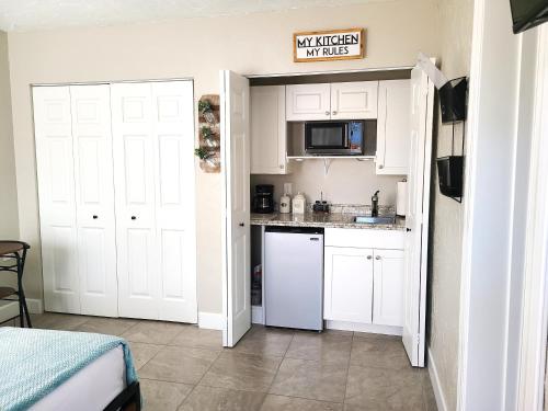 a kitchen with white cabinets and a white refrigerator at Studio University Pines at Sarasota in Sarasota