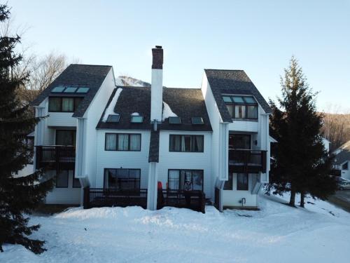 Une grande maison blanche dans la neige dans l'établissement Sunrise Mountain Village, à Killington