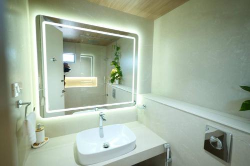 a white bathroom with a sink and a mirror at The Nova Heights in Kozhikode