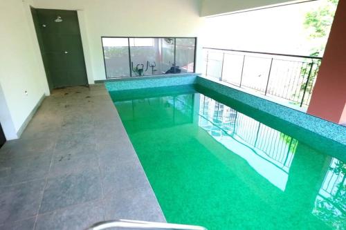 a swimming pool with green water in a house at The Nova Heights in Kozhikode