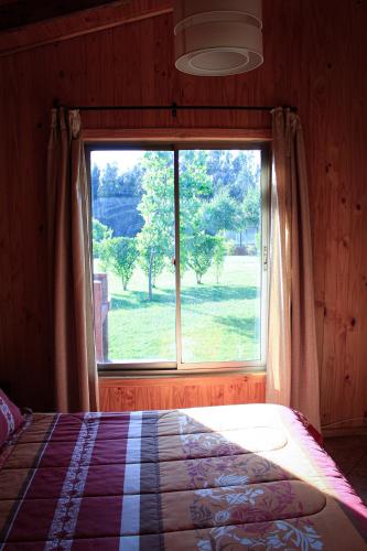 a bedroom with a bed and a large window at Cabañas Buenavista Quillón in Quillón