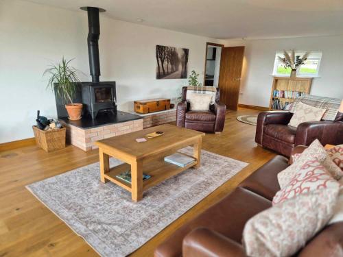 a living room with couches and a table and a fireplace at Poplars Cottage in Usk