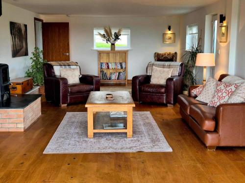 a living room with leather furniture and a coffee table at Poplars Cottage in Usk