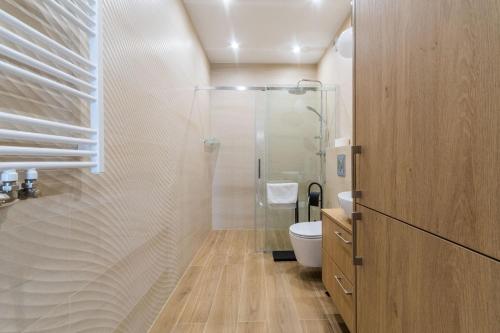 a bathroom with a glass shower and a toilet at Letnica - Seaside Apartment 1 by Grand Apartments in Gdańsk